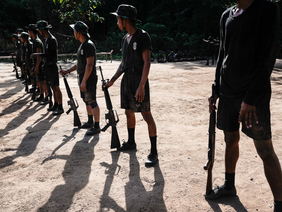 Guerilla-Kämpfer stehen in einer Reihe mit Waffen in der Hand