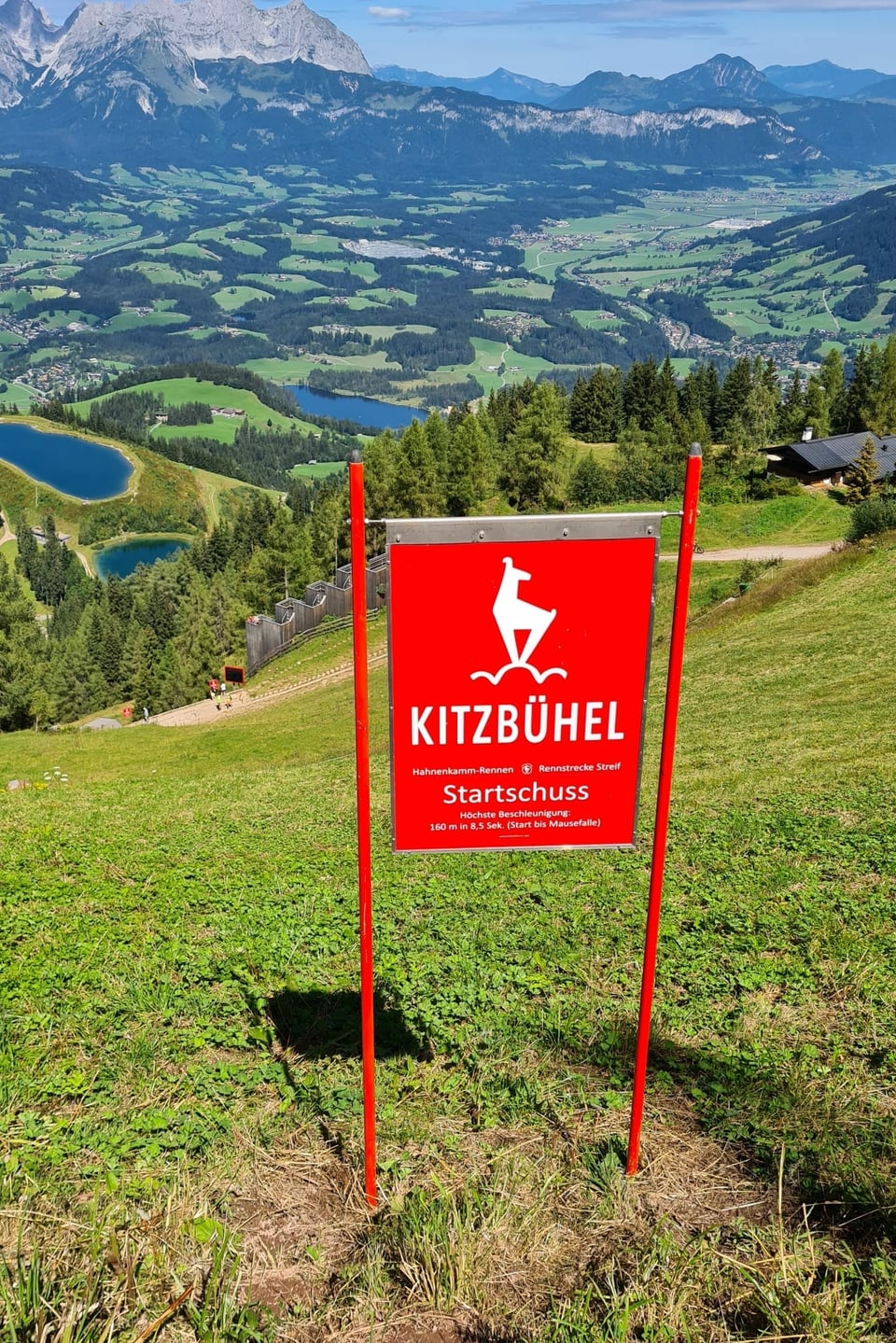 Aussicht ins Tal, im Vordergrund eine rote Tafel mit der Aufschrift "Kitzbühel".