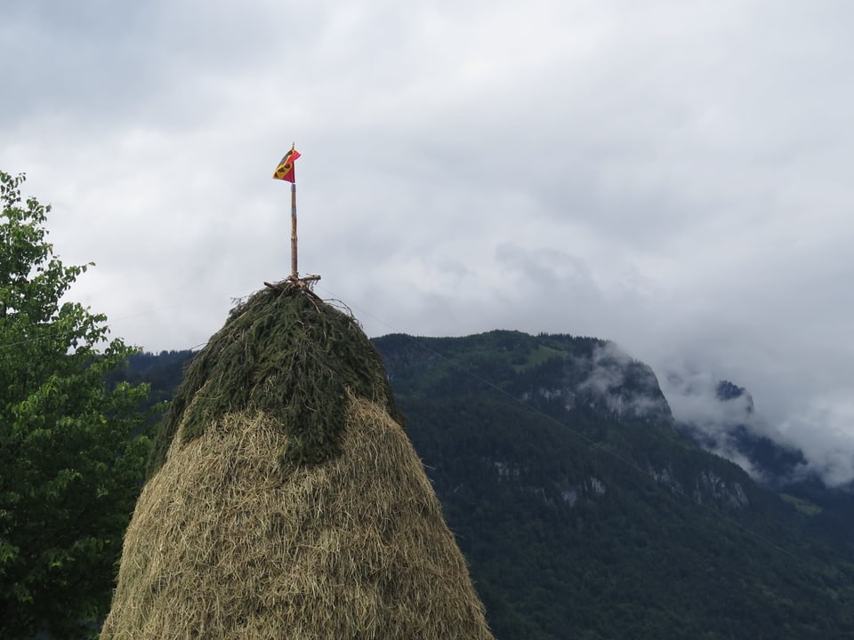 Heuhaufen mit Berner Fahne, im Hintergrund Berge 