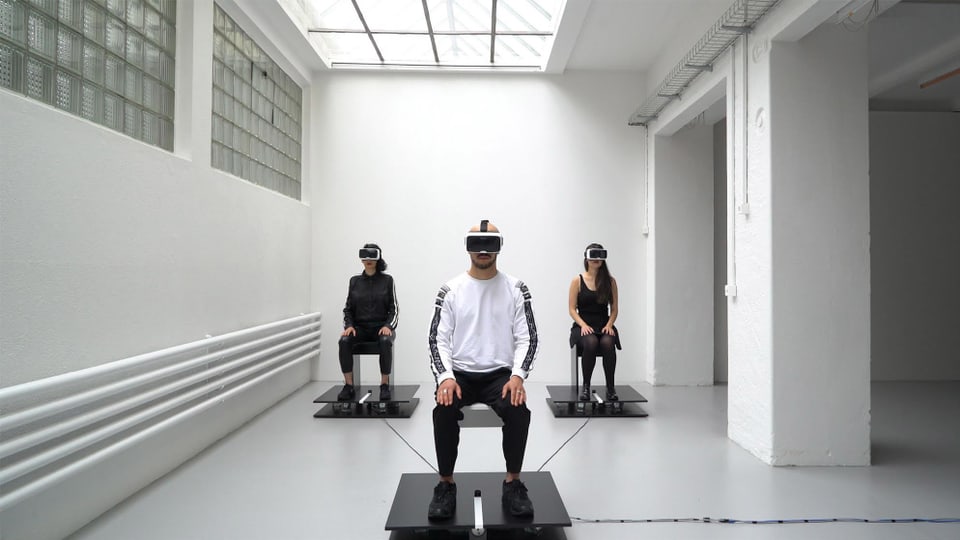 Drei Personen mit VR-Brillen sitzen in einem Raum. 