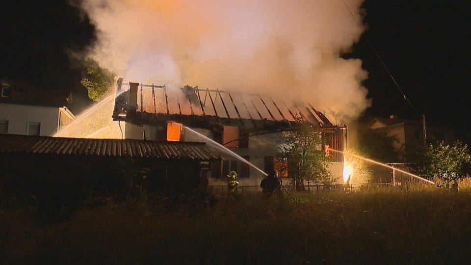 Ein niedergebranntes Wohnhaus, das von der Feuerwehr gelöscht wird