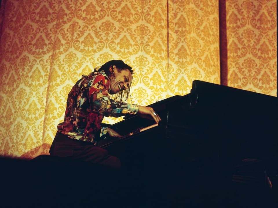 Pianist Howard Silver vor einem orangen Vorhang.
