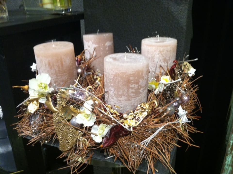 Ein Adventskranz mit vier grossen Kerzen in zarten lila Tönen.