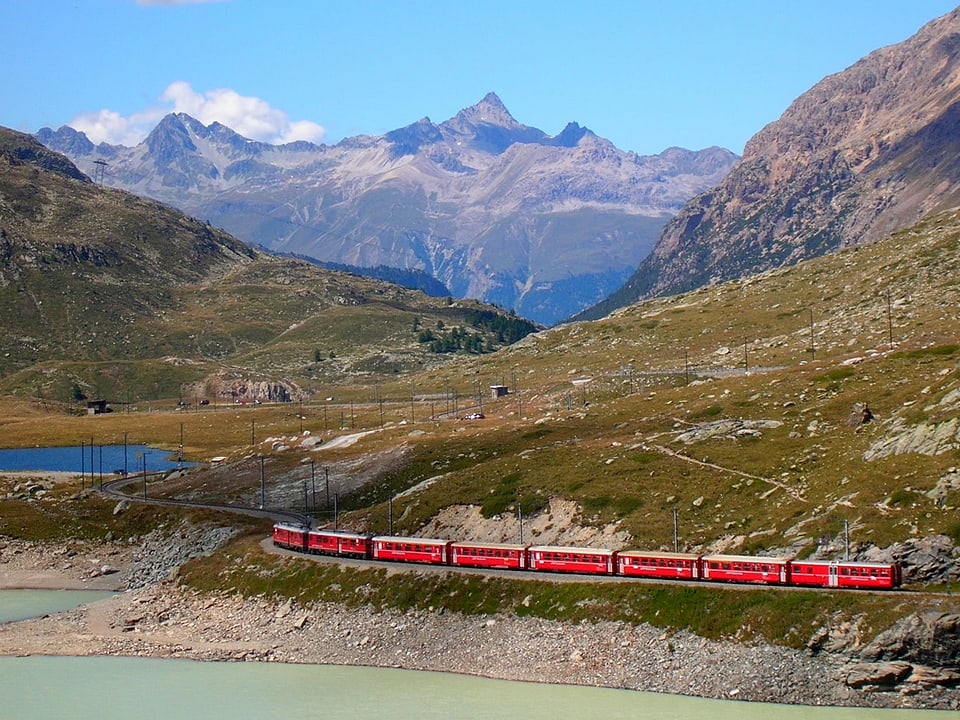 Ein Bernina-Express-Zug fährt am Ufer des Lago Bianco entlang.
