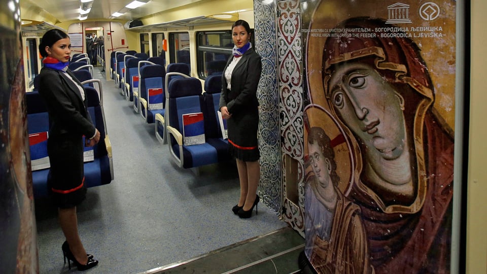 Zwei Zugbegleiterinnen in einem noch leeren Wagon. An den Wänden zu sehen sind religiöse Bilder.