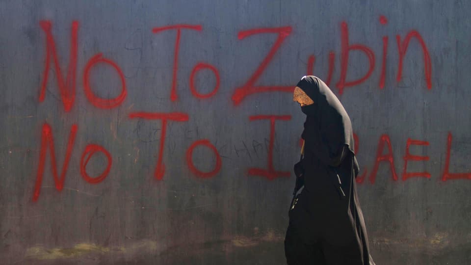 Ein verhüllte Muslimin geht an einem Graffiti vorbei mit dem Slogan: «No to Zubin, No to Israel.»