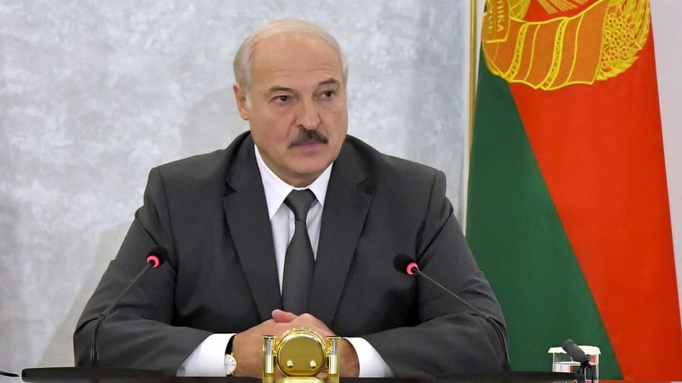 Lukaschenko sitzt an einem Pult und spricht zu den Medien.