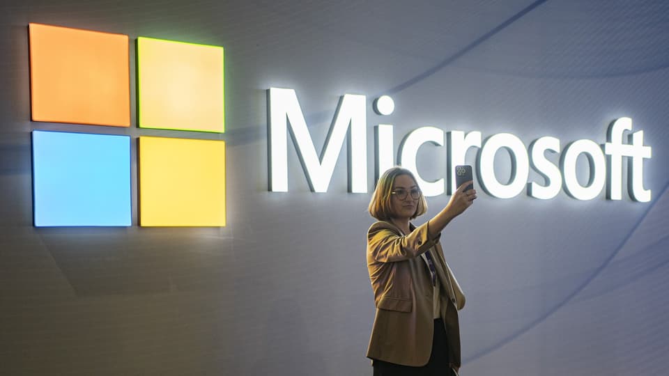 Frau macht Selfie vor Microsoft-Logo