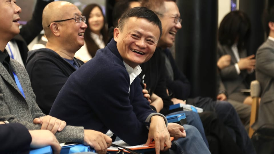 Jack Ma inmittten anderer Männer, er lacht.