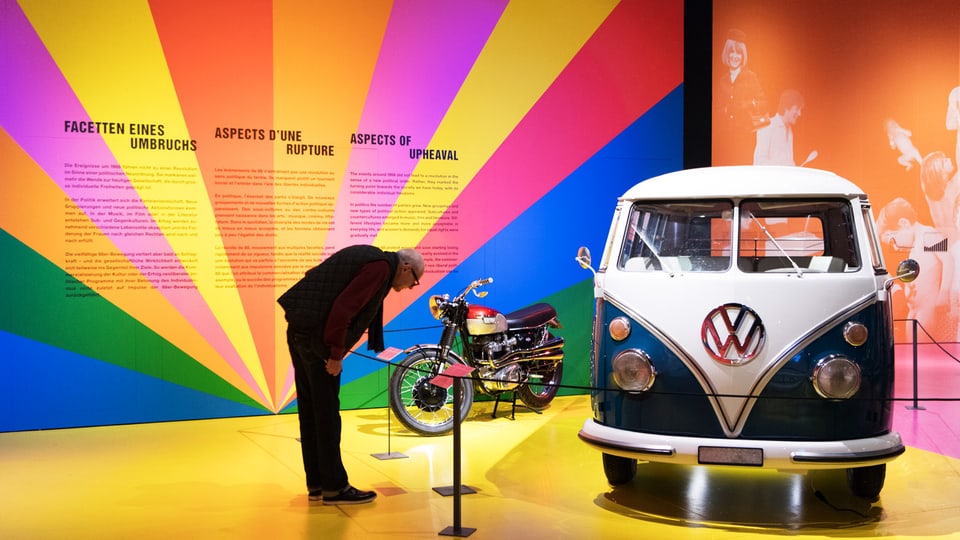 Ein Mann schaut sich einen VW-Bus in einem Ausstellungsraum an. 