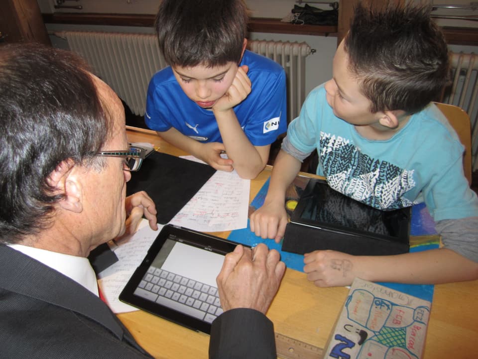 Zwei Schüler sitzen dem Stadtrat Gerold Lauber gegenüber, auf dem Tisch mehrere iPads.