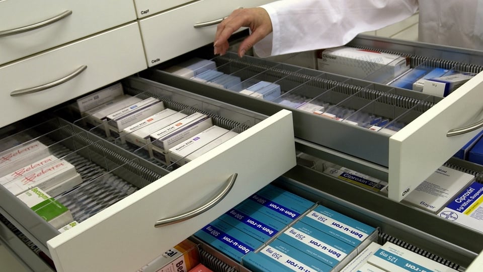 Eine Person öffnet verschiedene Medikamenten-Schubladen in einer Apotheke.