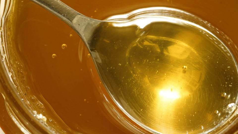 Ein Löffel voll Honig in einem Honigglas