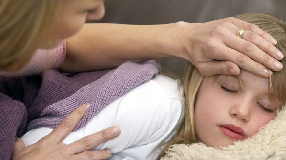 Mutter greift krankem Kind an die Stirn