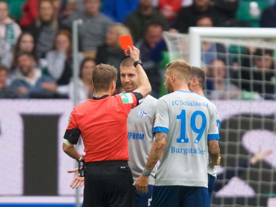 Der Schiedsrichter zeigt einem Spieler von Schalke die rote Karte.