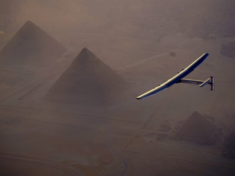 Eine Aufnahme des Solarflugzeugs in der Luft von oben. Es fliegt über Pyramiden in Ägypten.