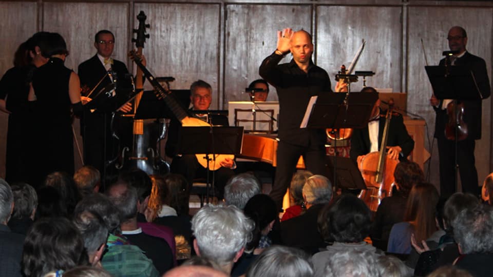 Stefano Montanari posiert auf der Bühne umgeben von Musikern.