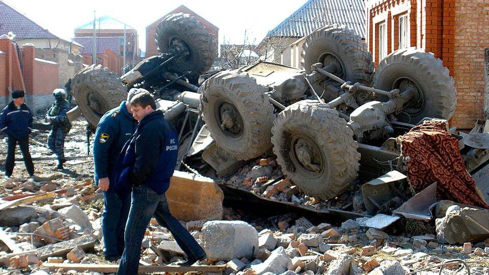 Russische Sicherheitskräfte stehen vor einem Lastwagenwrack