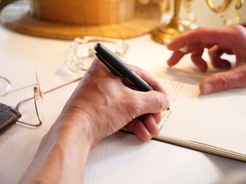 Eine Hand schreibt mit einem Füller in ein Heft.