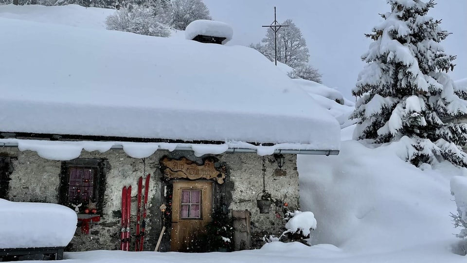 Berghütte mit viel Schnee auf dem Dach.