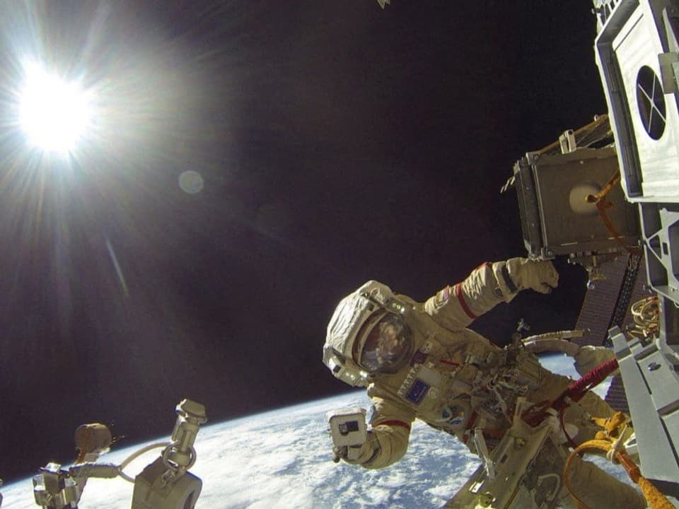 Ein Astronaut steht ausserhalb auf der Internationalen Raumstation. 
