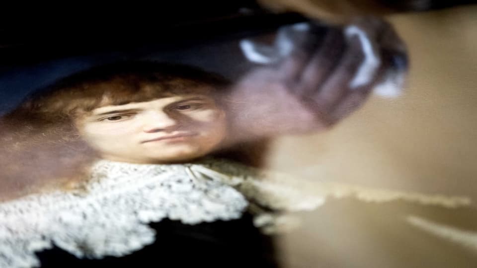 Ein Mitarbeiter putzt ein Rembrandt-Bild.