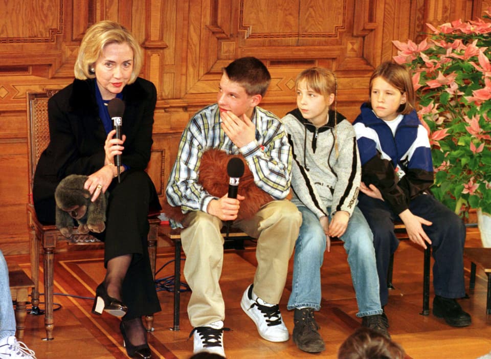 Hillary spricht zu den Kindern im Kinderpalament. Neben ihr sitzen drei Kinder und hören ihr zu.