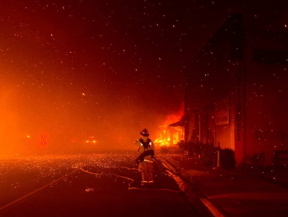 .Feuerwehrmann vor einem brennenden Gabäude.