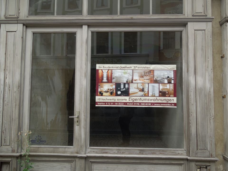 Ein Schild in einem Fenster kündigt den Umbau zu neuen Eigentumswohnungen an. 