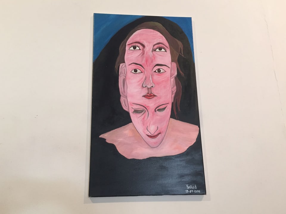 Das Foto zeigt ein gemaltes Bild. Darauf zu sehen ist eine Frau mit drei Gesichtern.