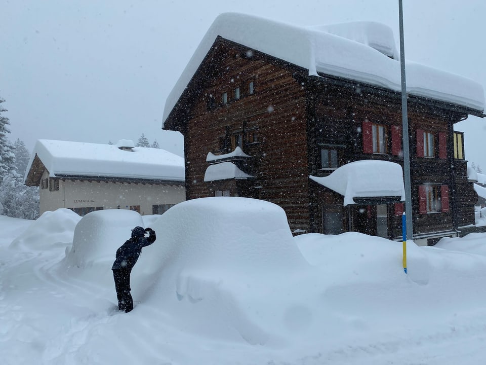 Tief verschneites Dorf mit Auto unter Schneemassen