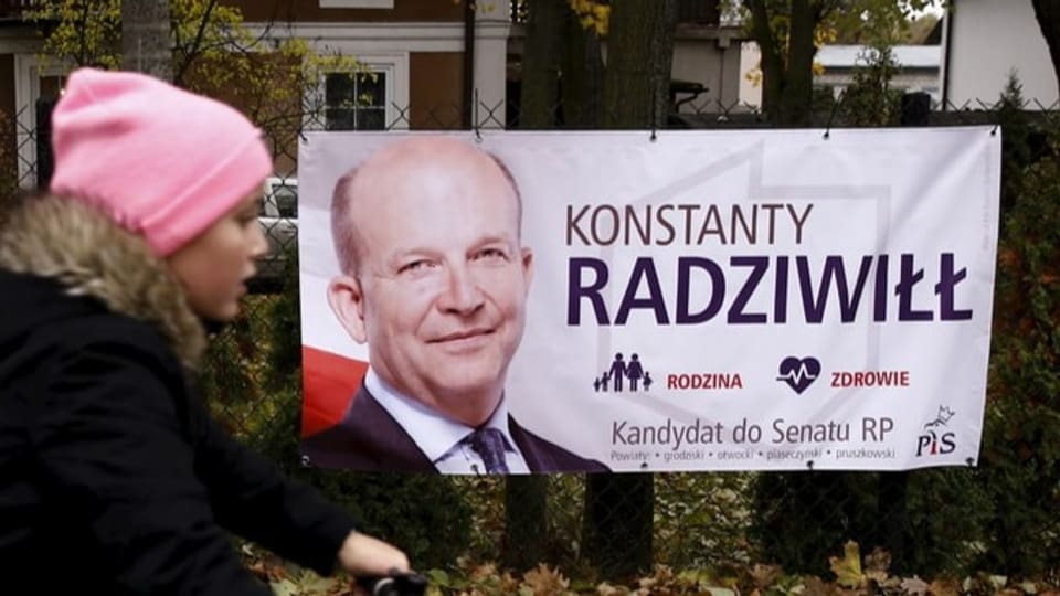 Ein Mädchen fährt mit dem Fahrrad vor einem Wahlplakat von Radzwill durch