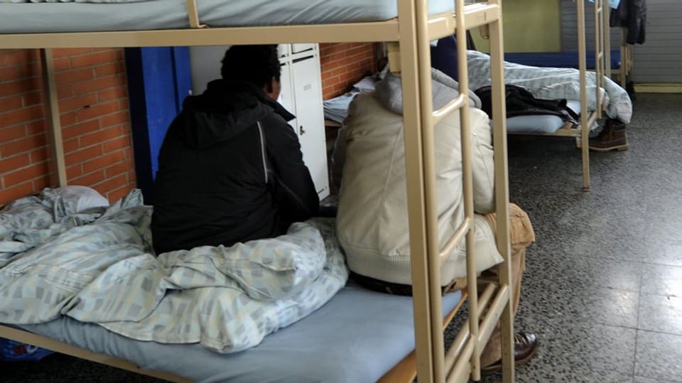 Asylsuchende auf einem Bett.