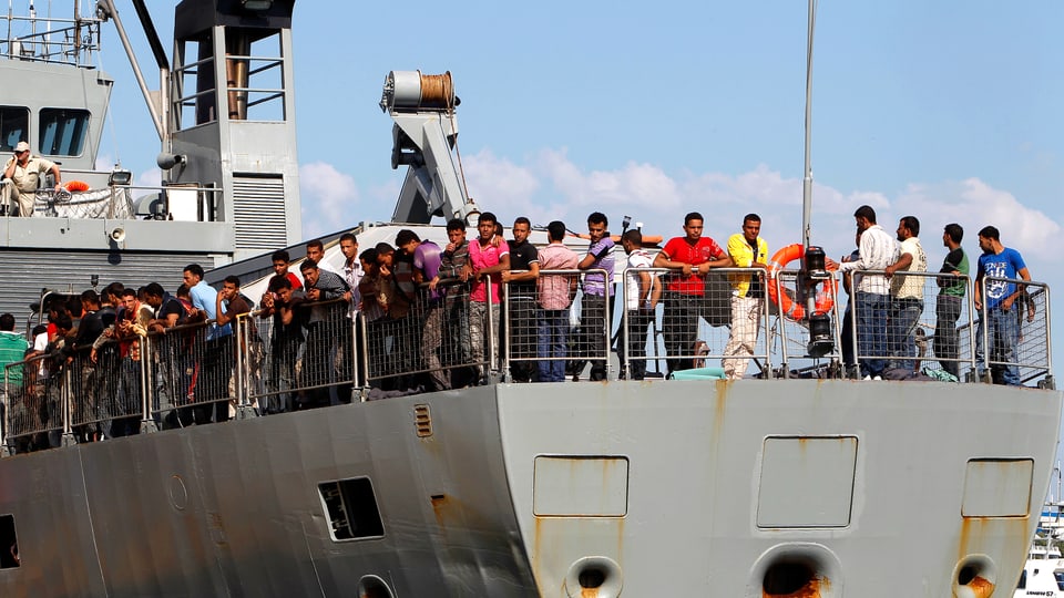 Heck eines kleineren türkischen Handelsschiffs im Hafen von Piräus. Das Deck ist voll mit Flüchtlingen.