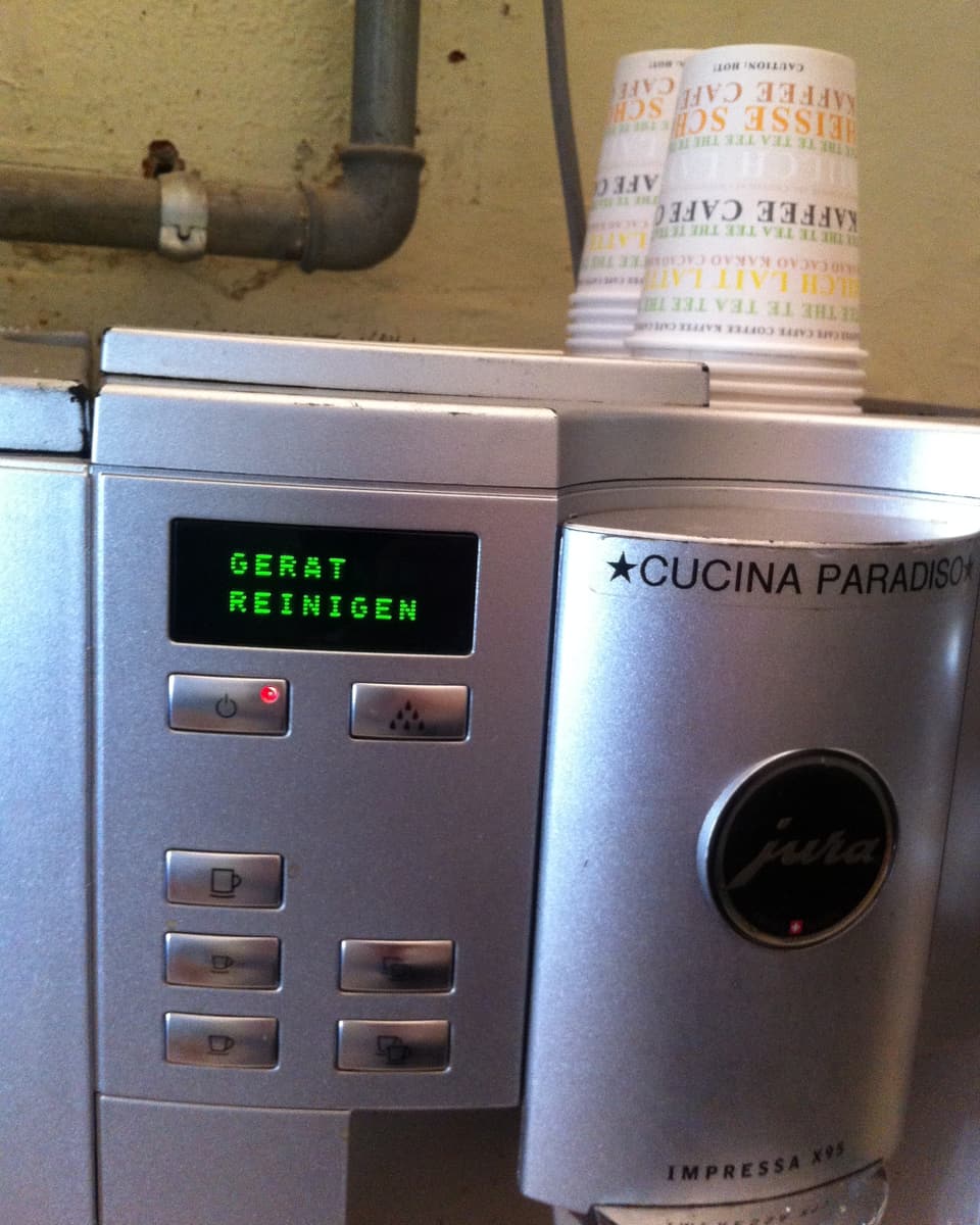 Eine Kaffemaschine. Die Anzeige leuchtet mit dem Schriftzug "Gerät reinigen".