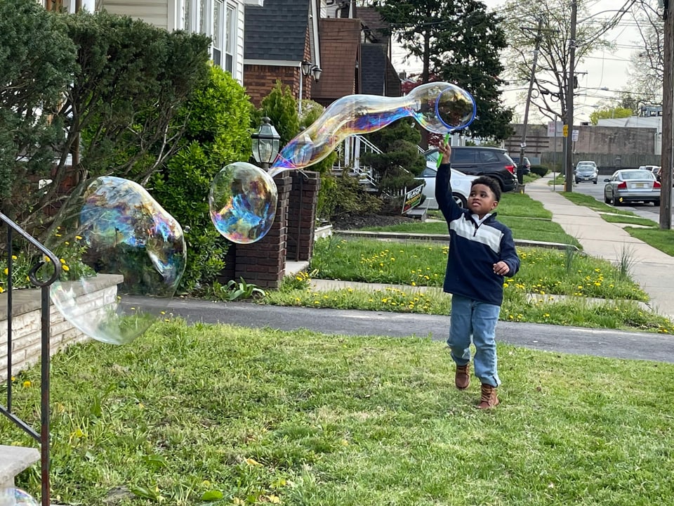 Ein Knabe spielt mit riesigen Seifenblasen in einer Strasse in Newark. 