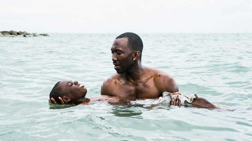 Filmszene: Ein Mann steht im Meer und hält einen Jungen über Wasser.