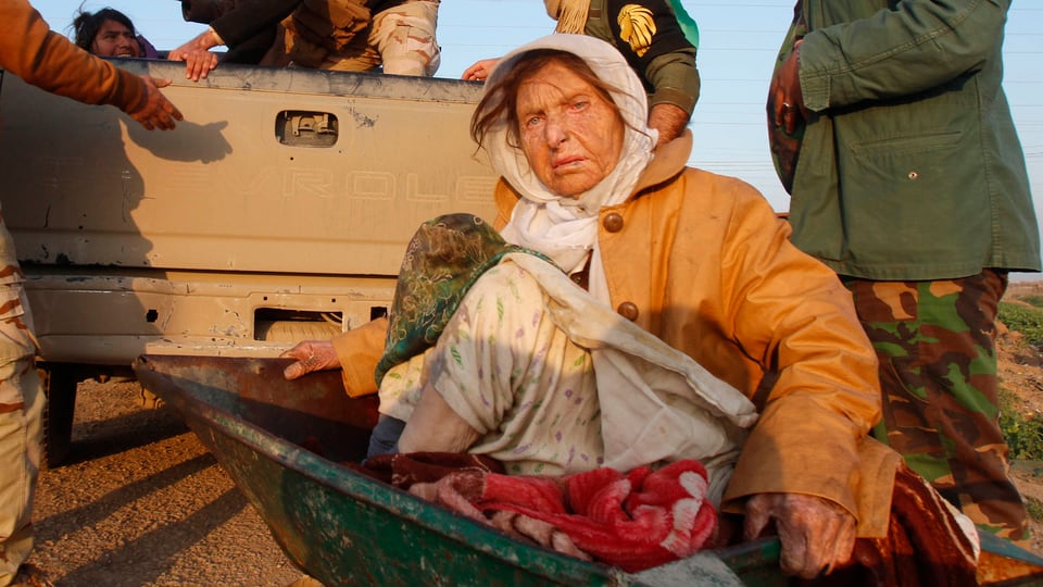 Eine ältere Frau sitzt in einer Schubkarre