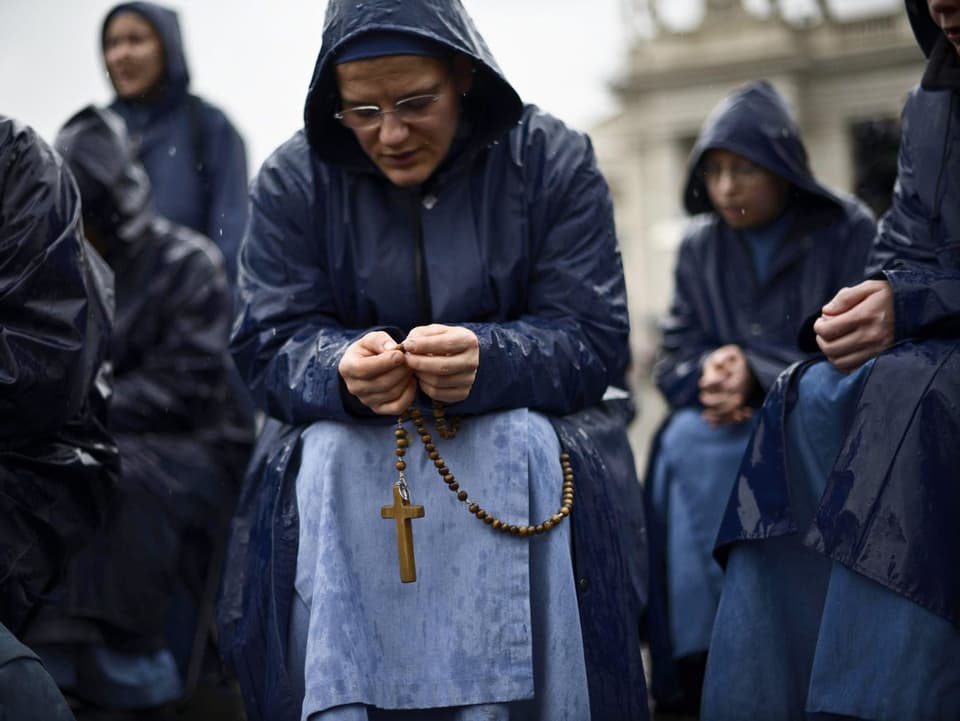 Den Rosenkranz betende Nonne im Regen auf dem Petersplatz.