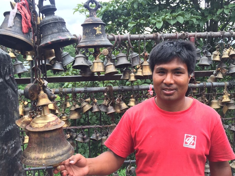 Handwerker Mahesh Shakia steht im roten T-Shirt in seinem Tempel im Pilgerort Bungamati und läutet eine Glocke.