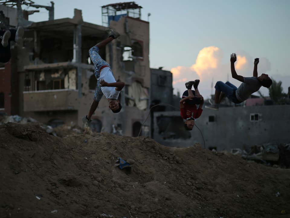 Drei Jugendliche trainieren Parkour im Gazastreifen.