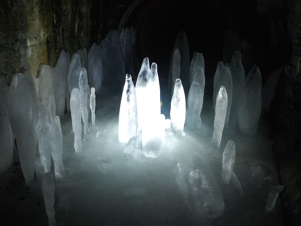 Beleuchtete Eisgebilde in einer Höhle. 