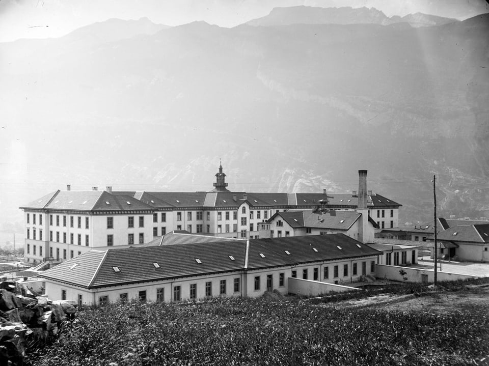 Schwarz-Weiss Bild einer Klinik vor Bergkulisse