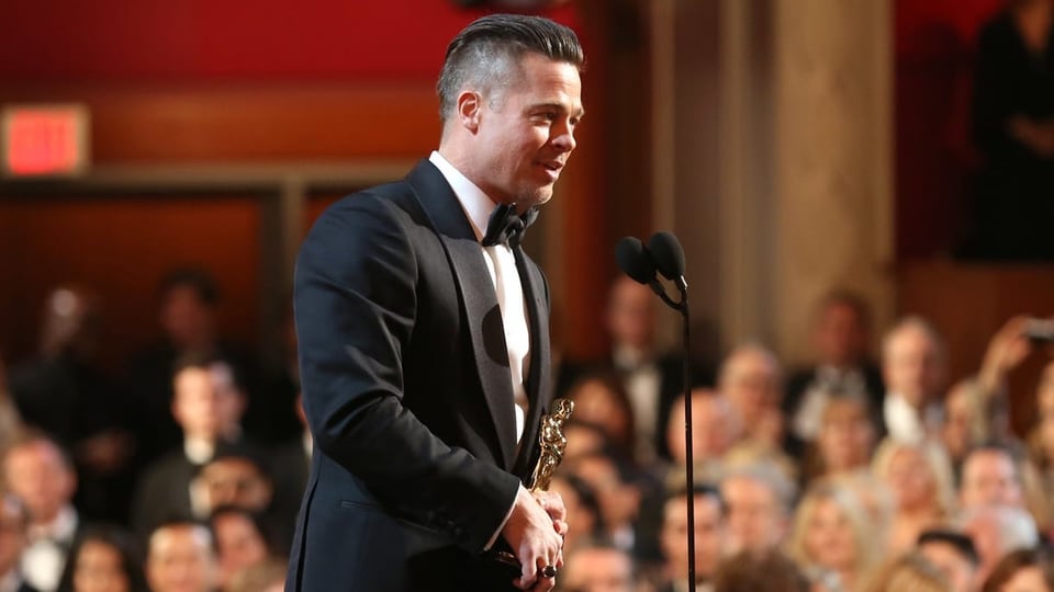 2014 gewinnt Brad Pitt den Oscar für «12 Years a Slave». Mann auf Bühne mit Oscar in der Hand.