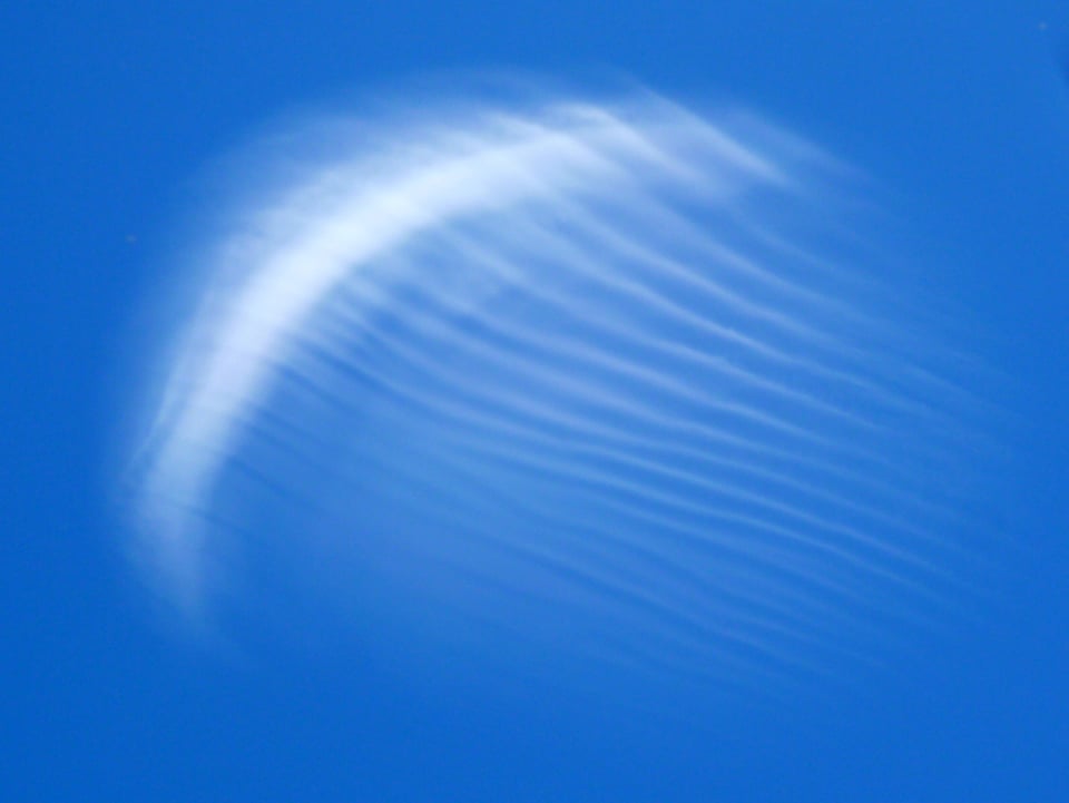 Am blauen Himmel zeigt sich eine dünne Wolke, welche grundsätzlich Sichelförmig ist. Von der Wolke gehen allerdings weisse Striche weg.