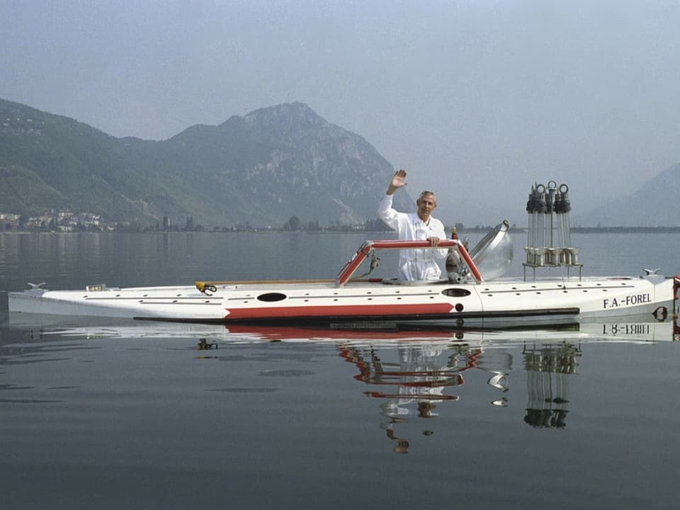 Älterer Herr in weissem Overall winkt aus einem U-Boot heraus