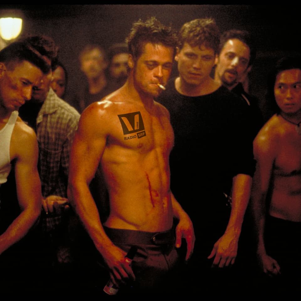 Brad Pitt mit nacktem Oberkörper und einem SRF Virus Logo auf der Brust