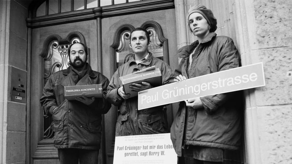 Drei Menschen halten Schilder in der Hand mit der Aufschrift «Paul Grüninger»