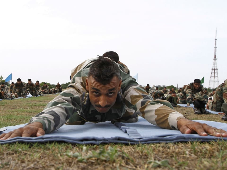 Soldat beugt seinen Oberkörper während einer Yoga-Übung nach vorn auf den Boden und streckt die Arme aus