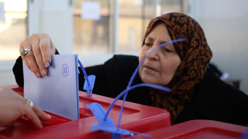 Eine Frau wirf ihren Wahlzettel in eine Urne